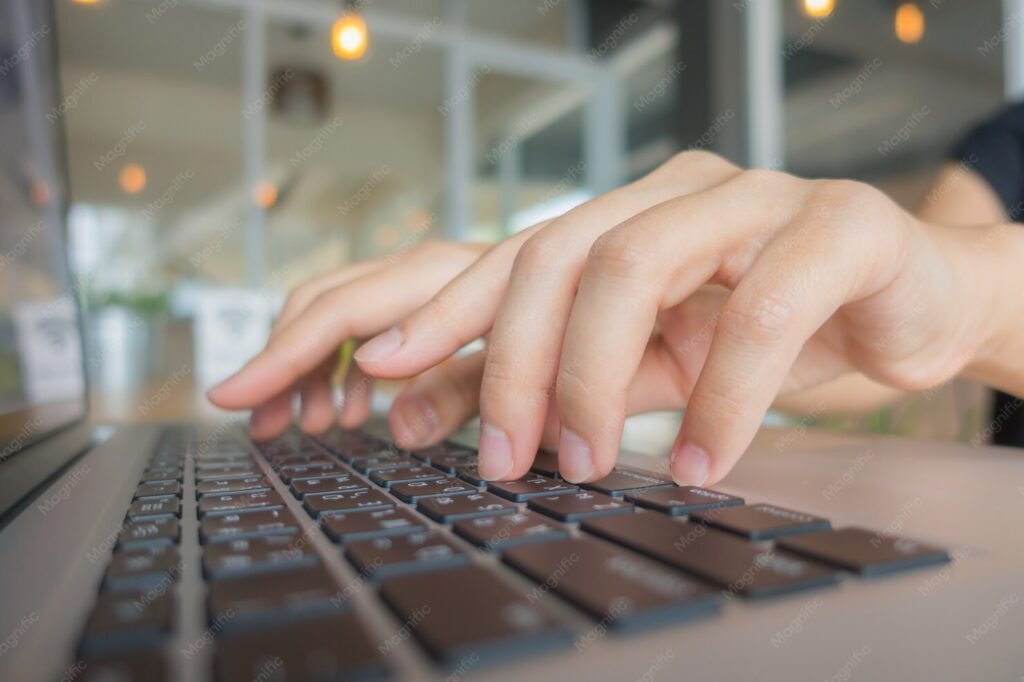 Primer plano de unas manos escribiendo en el teclado de un portátil.