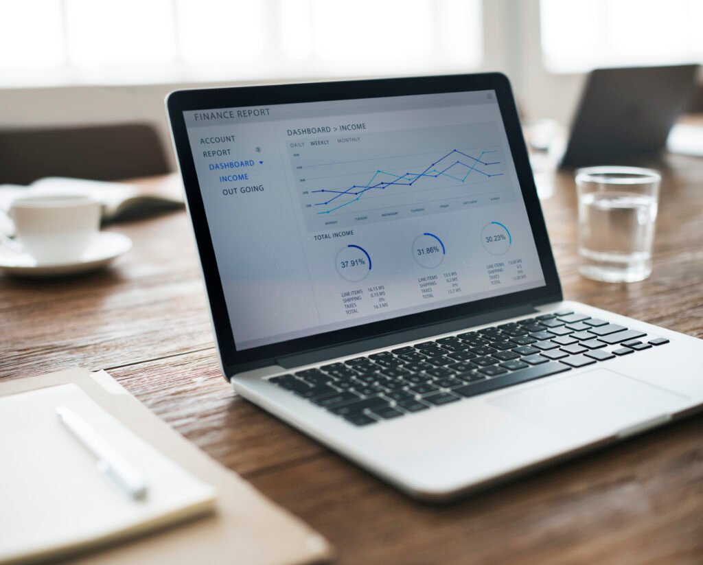 Un portátil muestra gráficos de evolución y varios indicadores sobre una mesa de trabajo.